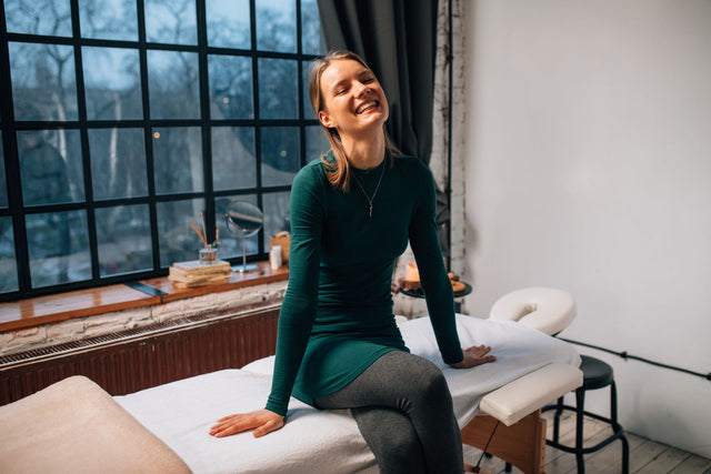 Client sitting on the treatment bed by the studio window, ready for her facial
